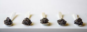 piatto bianco con cucchiaini di madreperla e caviale calvisius